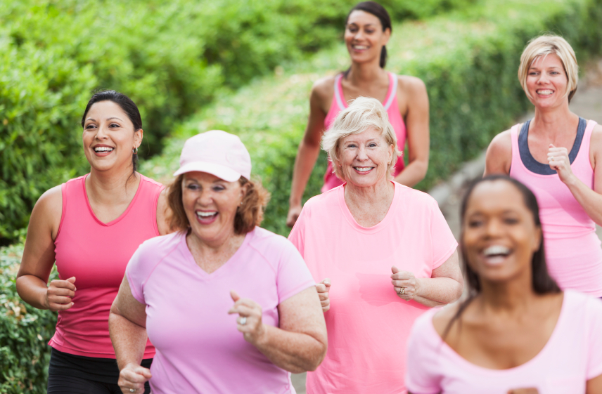A group of women wearing pink T-shirts are on a gentle jog outside.